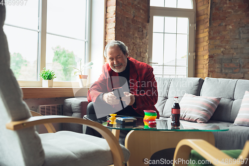 Image of Portrait of senior man with retro toys, meeting things from the past and having fun, exploring the lifestyle of the nineties, playing with rainbow spring toy and tetris