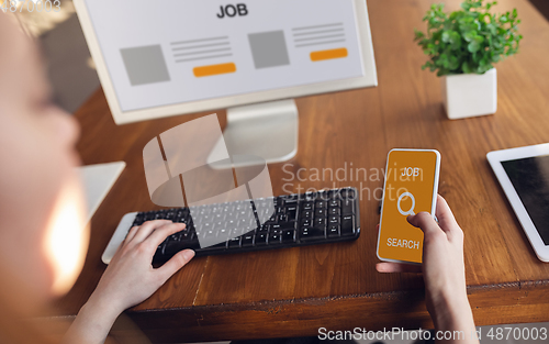 Image of Female hands scrolling phone while looking for a job during worldwide crisis of coronavirus pandemic. Find a job online. Business, internet and networking concept.