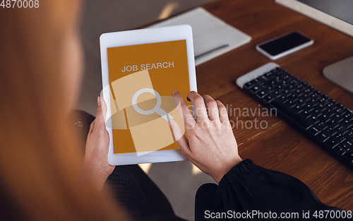 Image of Female hands scrolling tablet while looking for a job during worldwide crisis of coronavirus pandemic. Find a job online. Business, internet and networking concept.