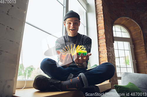 Image of Portrait of millenial boy using retro toys, meeting things from the past and having fun, exploring rainbow spring toy