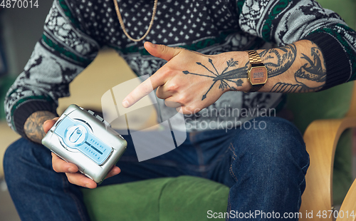 Image of Close up of millenial boy using retro toys, meeting things from the past and having fun, exploring music cassette player