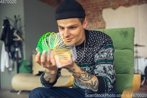 Image of Portrait of millenial boy using retro toys, meeting things from the past and having fun, exploring rainbow spring toy