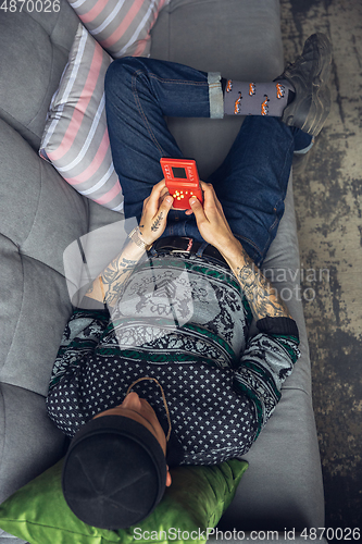 Image of Portrait of millenial boy using retro toys, meeting things from the past and having fun, exploring tetris game