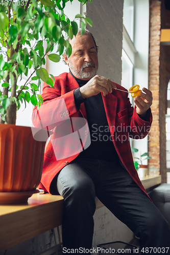 Image of Portrait of senior man with retro toys, meeting things from the past and having fun, exploring the lifestyle of the nineties, playing with yo-yo