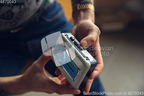 Image of Close up of millenial boy using retro toys, meeting things from the past and having fun, exploring music cassette player