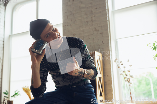 Image of Portrait of millenial boy using retro toys, meeting things from the past and having fun, exploring music cassette player