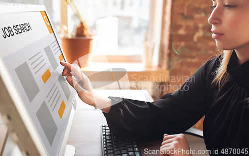 Image of Female hand touching screen while looking for a job during worldwide crisis of coronavirus pandemic. Find a job online. Business, internet and networking concept.