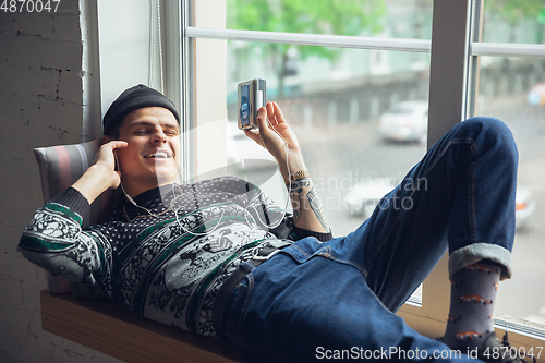 Image of Portrait of millenial boy using retro toys, meeting things from the past and having fun, exploring music cassette player