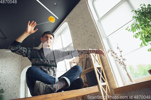 Image of Portrait of millenial boy using retro toys, meeting things from the past and having fun, exploring yo-yo game