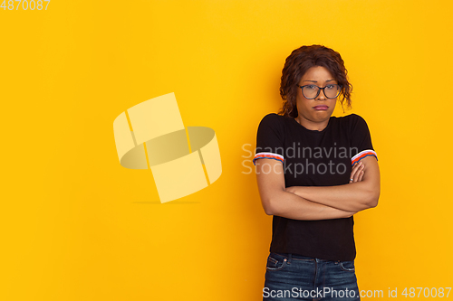 Image of African-american beautiful young woman\'s portrait on yellow studio background, emotional and expressive. Copyspace for ad.