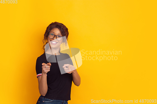 Image of African-american beautiful young woman\'s portrait on yellow studio background, emotional and expressive. Copyspace for ad.