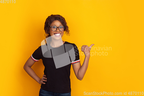 Image of African-american beautiful young woman\'s portrait on yellow studio background, emotional and expressive. Copyspace for ad.