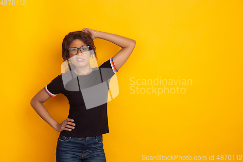 Image of African-american beautiful young woman\'s portrait on yellow studio background, emotional and expressive. Copyspace for ad.