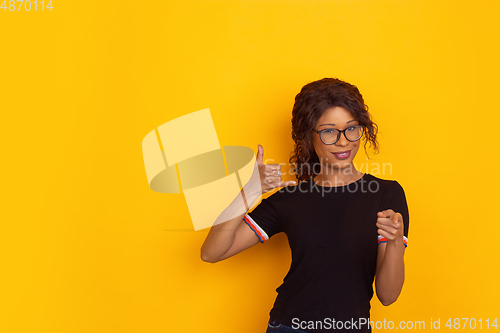 Image of African-american beautiful young woman\'s portrait on yellow studio background, emotional and expressive. Copyspace for ad.