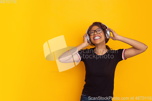 Image of African-american beautiful young woman\'s portrait on yellow studio background, emotional and expressive. Copyspace for ad.
