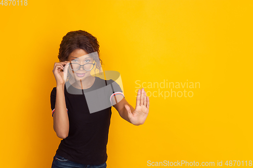 Image of African-american beautiful young woman\'s portrait on yellow studio background, emotional and expressive. Copyspace for ad.