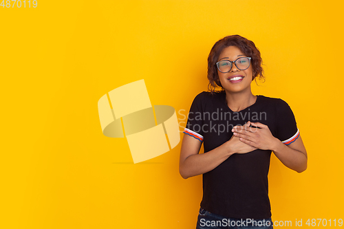 Image of African-american beautiful young woman\'s portrait on yellow studio background, emotional and expressive. Copyspace for ad.