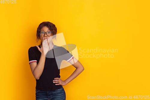 Image of African-american beautiful young woman\'s portrait on yellow studio background, emotional and expressive. Copyspace for ad.