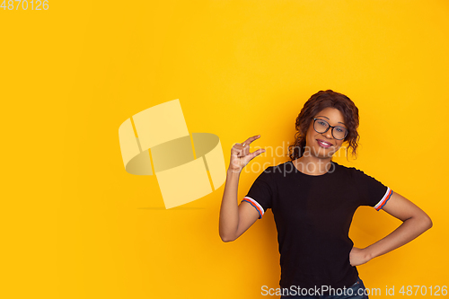 Image of African-american beautiful young woman\'s portrait on yellow studio background, emotional and expressive. Copyspace for ad.
