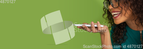 Image of African-american beautiful young woman\'s portrait on green studio background, emotional and expressive. Flyer with copyspace for ad.