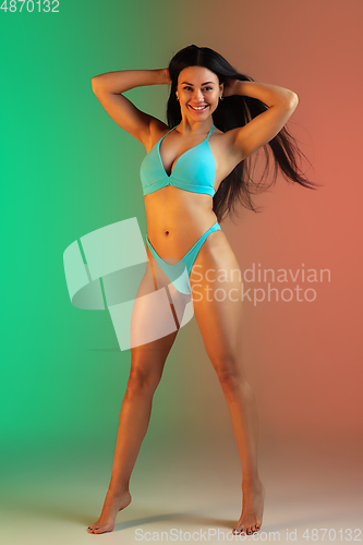 Image of Fashion portrait of young fit and sportive woman in stylish blue luxury swimwear on gradient background. Perfect body ready for summertime.