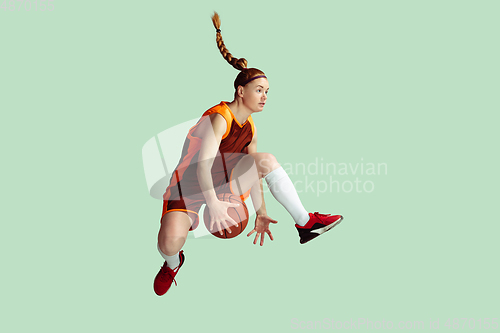 Image of Young caucasian female basketball player against mint colored studio background