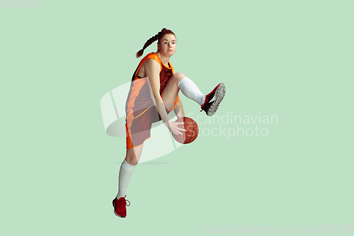 Image of Young caucasian female basketball player against mint colored studio background