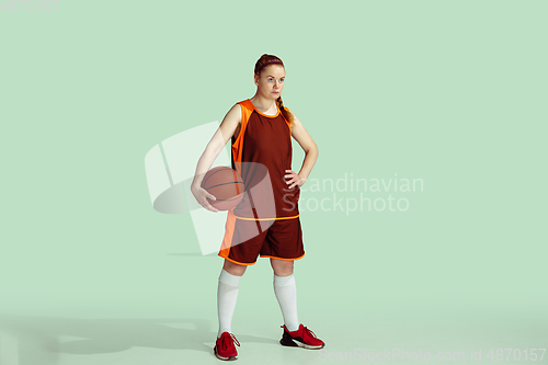 Image of Young caucasian female basketball player against mint colored studio background