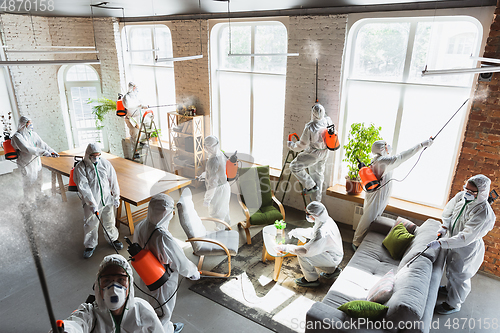 Image of Coronavirus Pandemic. A disinfectors in a protective suit and mask sprays disinfectants in the house or office