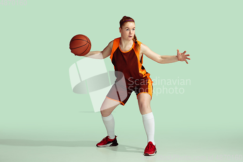 Image of Young caucasian female basketball player against mint colored studio background