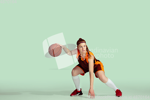 Image of Young caucasian female basketball player against mint colored studio background