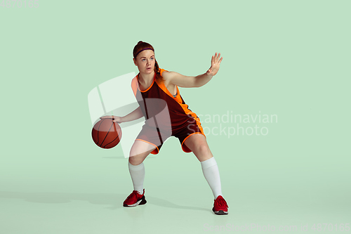 Image of Young caucasian female basketball player against mint colored studio background