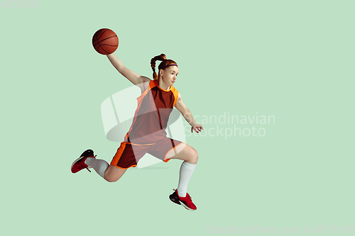 Image of Young caucasian female basketball player against mint colored studio background