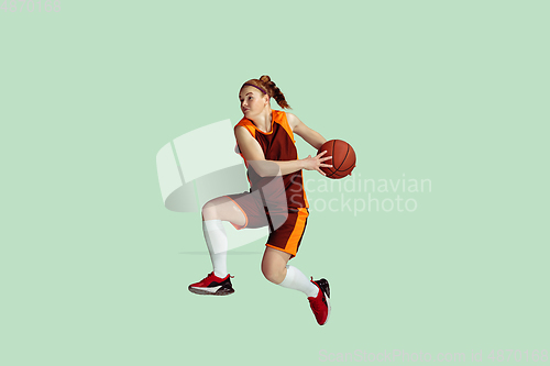 Image of Young caucasian female basketball player against mint colored studio background