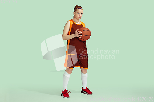 Image of Young caucasian female basketball player against mint colored studio background