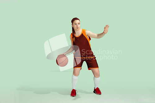 Image of Young caucasian female basketball player against mint colored studio background