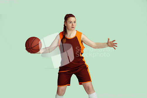 Image of Young caucasian female basketball player against mint colored studio background