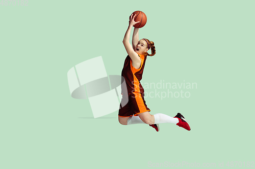 Image of Young caucasian female basketball player against mint colored studio background