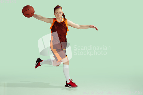 Image of Young caucasian female basketball player against mint colored studio background