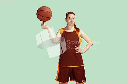 Image of Young caucasian female basketball player against mint colored studio background