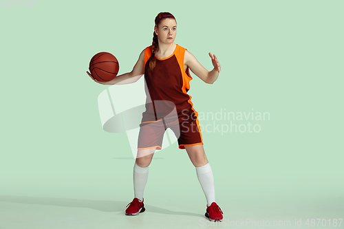Image of Young caucasian female basketball player against mint colored studio background