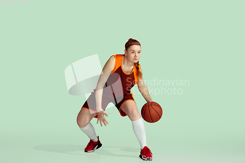 Image of Young caucasian female basketball player against mint colored studio background