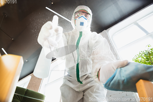 Image of Coronavirus Pandemic. A disinfector in a protective suit and mask sprays disinfectants in the house or office