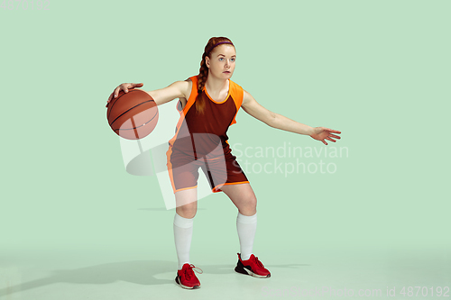 Image of Young caucasian female basketball player against mint colored studio background