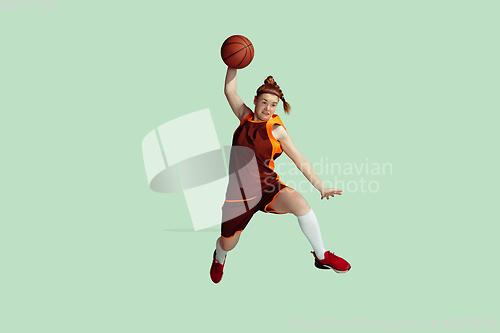 Image of Young caucasian female basketball player against mint colored studio background