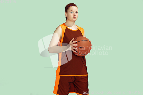 Image of Young caucasian female basketball player against mint colored studio background