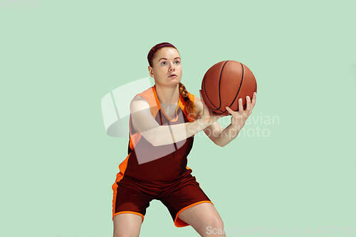 Image of Young caucasian female basketball player against mint colored studio background