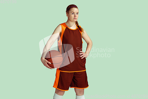 Image of Young caucasian female basketball player against mint colored studio background
