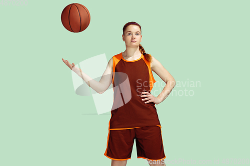 Image of Young caucasian female basketball player against mint colored studio background