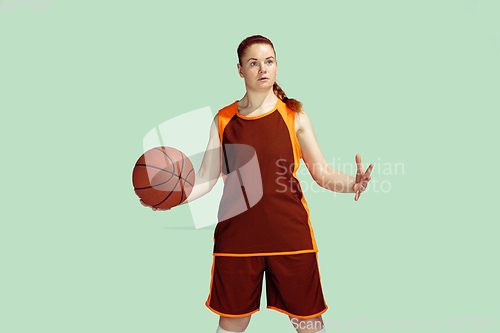 Image of Young caucasian female basketball player against mint colored studio background